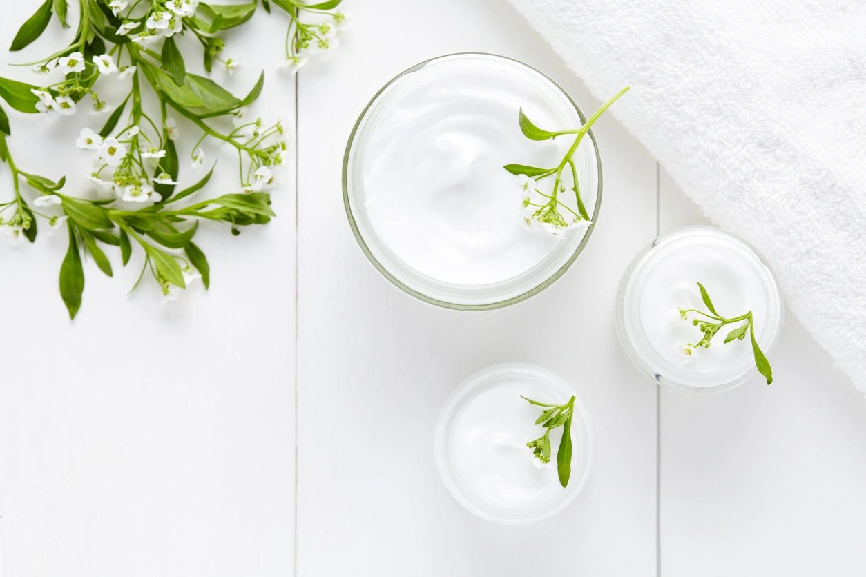 A white table with two glasses of milk and some green leaves.