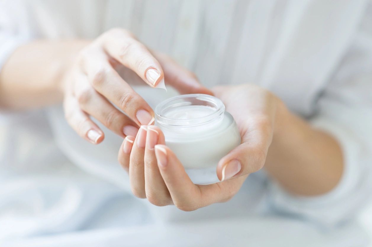 A woman holding a jar of cream in her hands.