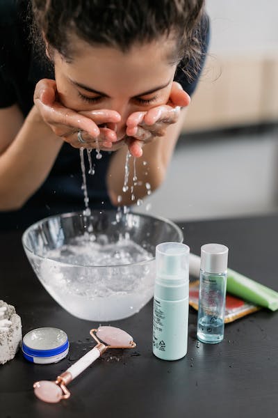 Woman washing her face with water.