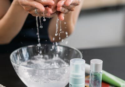 Woman washing her face with water.